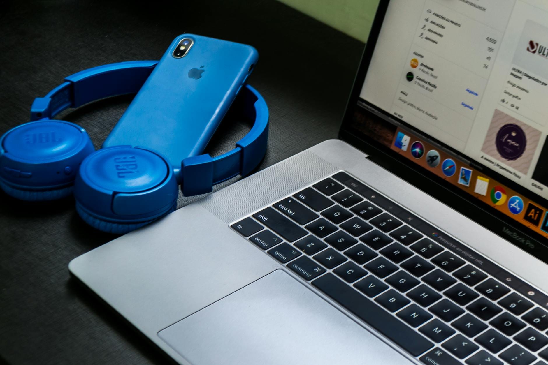 Bluetooth w laptopie nie widzi słuchawek: sprawdź sterowniki, usługę i tryb parowania Laptop na biurku obok niebieskich słuchawek Bluetooth i smartfona